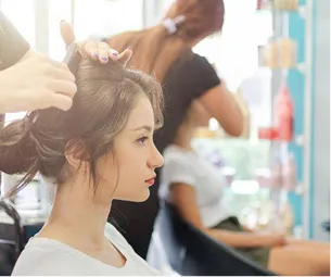 Jeune femme dans un salon de coiffure, une coiffeuse lui arrange les cheveux au Mans dans la Sarthe 72