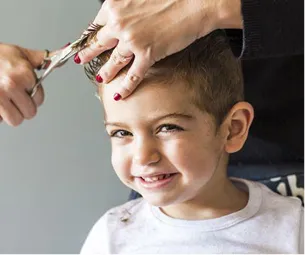 Un jeune garçon souriant se fait couper les cheveux par un adulte. au Mans dans la Sarthe 72