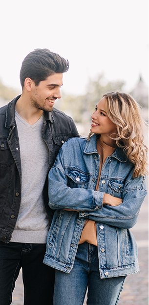 Jeune couple souriant se regardant affectueusement, l'homme en veste noire, la femme en jean au Mans dans la Sarthe 72
