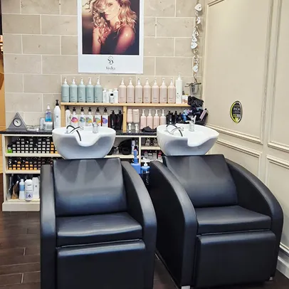 Deux chaises de lavage de cheveux noires avec lavabos blancs dans un salon.
