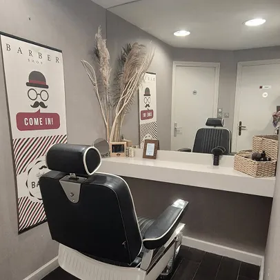 Chaise de barbier noire et blanche devant un miroir et une affiche BARBER SHOP.